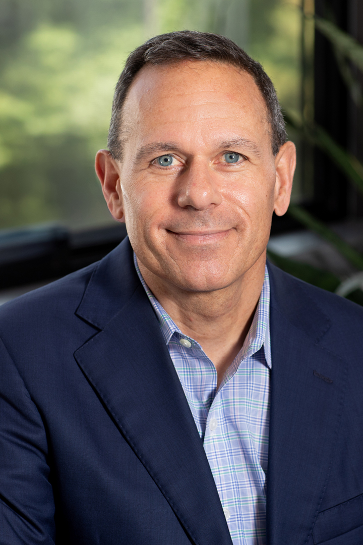 Headshot of Brian Lavoie smiling with short hair and wearing a dark blue blazer with blue and green button down shirt with no neck tie